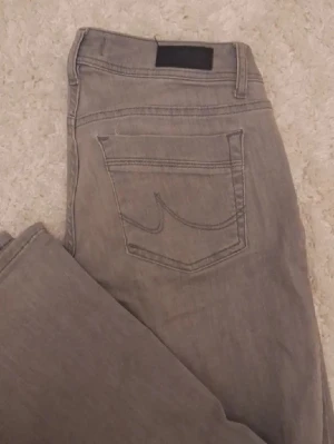 Grå lågmidjade  bootcut  jeans från LTB - Säljer ett par grå jeans från LTB med bootcut ben  och klassisk bakficka med den ikoniska sömmen. Jeansen är lågmidjade  och är tillverkade i mjukt denimtyg som sitter bekvämt. Perfekta för en avslappnad och stilren look.