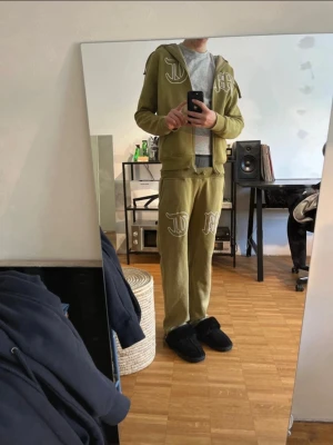 Olive grön Tuttolente tracksuit - Olivgröna mjukisbyxor från Tuttolente med stora vita tryck på ena benet. Byxorna har resår i midjan och raka ben med dragsko vid benslut. Tillverkade i mjukt bomullsmaterial för maximal komfort. Perfekta för en avslappnad och trendig stil.