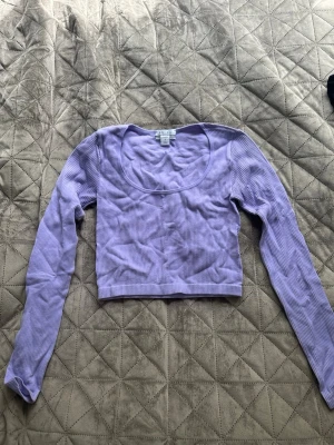 Ljuslila ribbad croppad topp Amisu - Superfin ljuslila croppad topp från Amisu med lång ärm och ribbad struktur. Toppen har en rund, djup ringning och är perfekt för dig som gillar en trendig och enkel stil. Passar snyggt till både jeans och kjol.