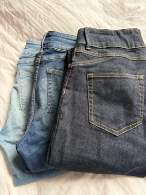 3-pack Lilly jeans från Lindex i olika blå nyanser - Säljer ett 3-pack Lilly jeans från Lindex i olika blå tvättar – ljusblå, mellanblå och mörkblå. Klassisk femficksmodell med kontrastsömmar och normal midja. Perfekta basjeans i mjukt denimtyg som passar till allt.