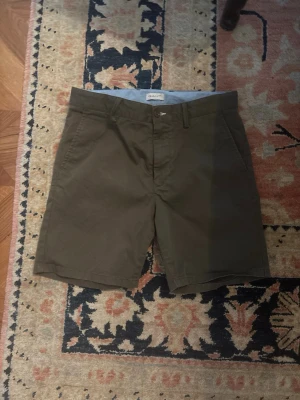 Olivgröna shorts från Gant - Snygga olivgröna shorts från Gant med klassisk passform och diskreta fickor på sidorna. Tillverkade i bomull för en skön känsla och perfekt för varma dagar. Stängs med knapp och dragkedja framtill.