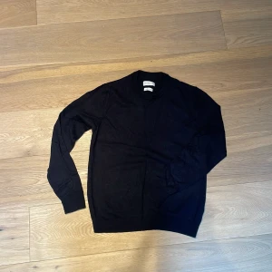 Mörkblå stickad tröja These Glory Days - Mörkblå stickad tröja från These Glory Days med rund halsringning och ribbade muddar vid ärmslut och nederkant. Tröjan har en klassisk, enkel design och är tillverkad i mjukt material som passar perfekt till lager på lager.
