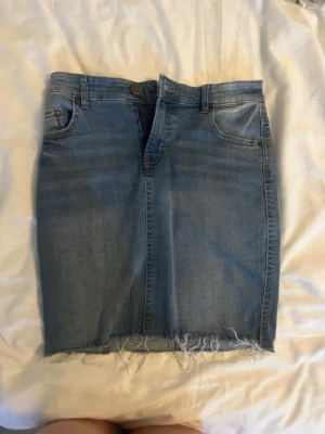 Blå jeanskjol med rå kant - Snygg blå jeanskjol i klassisk femficksmodell med rå, fransig kant nedtill. Kjolen har normal passform och bälteshällor i midjan. Perfekt för dig som gillar en avslappnad och trendig stil.🛍️💖