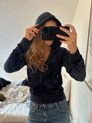 Mörkblå hoodie från Juicy Couture - Snygg mörkblå hoodie i velour från märket Juicy Couture, med dragkedja framtill och fickor på sidorna. Hoodien är använd cirka 2 gånger och är i mycket fint skick. ”Classic Velour Robertson Zip Hoodie Night Sky” 