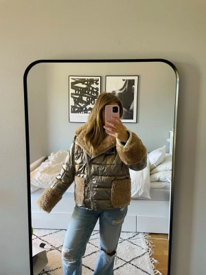 Glansig pufferjacka med teddy-detaljer - Säljer en unik pufferjacka i glansigt guldigt material med stora teddy-detaljer i beige på krage, ärmslut och fickor. Jackan har dragkedja framtill och oversized passform som ger en cool och trendig look. Perfekt för dig som vill sticka ut i vinter! 🤍(stor i storleken) 