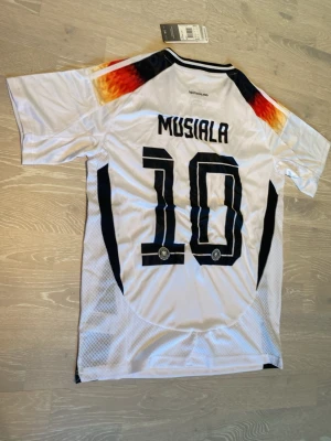 Tysklands fotbollströja Musiala 10 - Tja! Säljer en helt ny Tyskland VM 2026  Musiala #10  T-shirt.                                                                                  Den är helt ny , så den har sjuka detaljer! 🤩.                                                                                  Storleken Är Small, och jag skickar inom 24 Tim💨🤩 hör av dig!