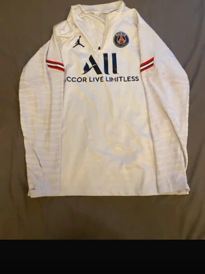 Vit PSG träningströja Jordan - Väldigt snygg träningströja från PSG. Texterna är lite slitna ifrån tvättmaskin därav det låga priset. Finns ett par helt oanvända byxor till tröjan, på min sida:)