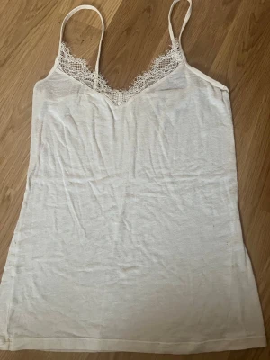 Vit intimissimi  linnetopp m spets  - Säljer en enkel och stilren vit linnetopp från Intimissimi med tunna axelband och v-ringning dekorerad med spets. Toppen är i mjuk bomull och passar perfekt till både jeans och kjol. Superskön och lätt att matcha med olika outfits. Jättefint skick ❤️