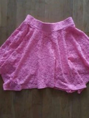 Kjol - Söt rosa kjol med volang och bred midjeresår. Kjolen är gjord i spetsmaterial och har en luftig, kort modell som passar perfekt till varmare dagar. Enkel att matcha med både toppar och sneakers.