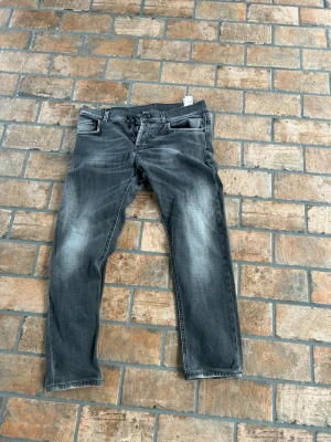 Grå dondup jeans - Säljer ett par grå dondup med snygg tvättad look och raka ben. Jeansen har fem fickor, bälteshällor och dragkedjegylf. Passar perfekt till en avslappnad stil och är lätta att matcha med olika plagg. 