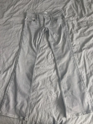 Ljusgrå lågmidjade bootcut jeans från Gina Tricot - Säljer ett par ljusgrå bootcut jeans från Gina Tricot. Jeansen har klassisk femficksmodell, snygga sömmar på bakfickorna och vida ben. De är endast provade och aldrig använda😊 