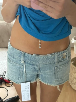 Lågmidjade jeansshorts med rå kant - Säljer ett par ljusblå lågmidjade jeansshorts från Gina tricot