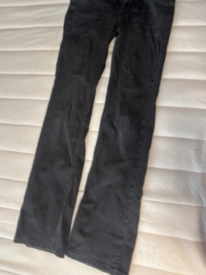 Svarta bootcut jeans Jessica W28 L33 - Säljer ett par svarta bootcut jeans från Jessica. Jeansen har klassisk femficksmodell, normal midja och dragkedja med knapp. Materialet är mjukt och stretchigt för extra komfort. Perfekta för dig som gillar en tidlös och avslappnad stil.