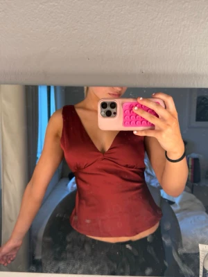 Vinröd topp i satin - Snygg vinröd topp i satin, man kan välja hur tajt den ska sitta i midjan då man knyter den🥰