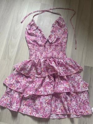 Somrig blommig rosa volangklänning - Supersöt kort klänning med blommigt mönster i rosa från SHEIN, perfekt midsommarklänning. Den har halterneck, smockad midja och flera volanglager. Perfekt till sommaren, endast provad!