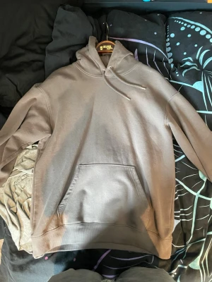 Mörkgrå   hoodie med magficka - En stilren beige hoodie från H&M med klassisk huva och dragsko. Hoodien har en stor magficka framtill och ribbade muddar vid ärmslut och nederkant. Perfekt för en avslappnad och trendig look. Tillverkad i mjukt bomullsmaterial. Priset är inte huggit i sten och jag tar gärna emot prisförslag.