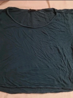 Mörkgrön croppad t-shirt - En enkel croppad t-shirt med rund halsringning. T-shirten har korta ärmar och är tillverkad i mjukt bomullsmaterial. Perfekt för en avslappnad och stilren look.