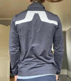 J.Lindeberg Mid Layer / Golftröja – Strl S - Säljer en stilren och funktionell långärmad tröja från J.Lindeberg. Perfekt som mellanlager på golfbanan, under träning eller till vardags. Stretchigt och bekvämt material med kort dragkedja i halsen och snygga detaljer på ärm och rygg.  Märke: J.Lindeberg Storlek: S Färg: Mörkblå Skick: Mycket fint skick  Lätt och följsam passform som fungerar året runt. Diskret design med J.Lindeberg-logga på ärm och krage.