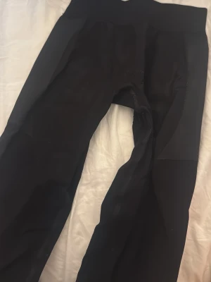 Svarta leggings från H&M Move - Säljer ett par svarta leggings från H&M Move med bred midjeresår och stretchigt material. Perfekta för träning eller chill, med diskreta sömmar och smickrande passform. Materialet är mjukt och följsamt för maximal komfort.