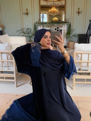 Mörkblå abaya  - Elegant mörkblå abaya med vida ärmar och vackra spetsdetaljer vid ärmsluten. Klänningen har en lös passform och är tillverkad i ett mjukt, sammetsliknande material som ger en lyxig känsla. Perfekt för dig som vill ha en modest och stilren look.