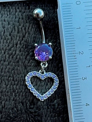 NY oanvänd Navelpiercing med hänge | Kirurgiskt stål | Hjärta och lila stenar  - 💕30% Bundle-rabatt vid köp av minst 2 artiklar. ⭐️NY oanvänd piercing i kirurgiskt stål; rostfritt och säkert för läkta piercingar.                               📏MÅTT ⭕️Stavens längd: 10mm ⭕️Stavens tjocklek: 1,6mm ⭕️Smyckets totala längd: 35mm                                                                         🤍Färger: Silver och lila                                                          💌Skickas spårbart via Plick SafePay.