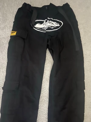 Corteiz Guerillaz Cargo Pants - Säljer ett par riktigt snygga Corteiz Guerillaz Cargo Pants i svart färg, storlek M. Byxorna är endast använda ett fåtal gånger och är i mycket bra skick utan slitage, hål, fläckar eller andra defekter.  De är lite skrynkliga på bilderna eftersom de mest har legat förvarade, men det försvinner enkelt vid användning eller efter tvätt.  Perfekta cargo-byxor med flera fickor och den klassiska Corteiz-designen. Bekväma, stilrena och eftertraktade.