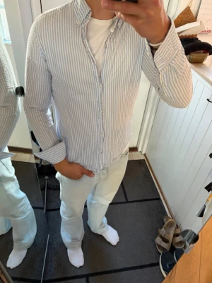 Vit/blå randig skjorta från Riley - Riktigt schysst skjorta som tyvärr blivit för liten på mig. Inga skador. Storlek M men sitter som S.