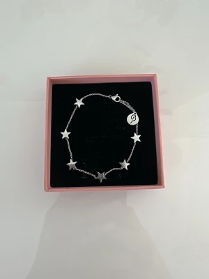 Silverfärgat armband med stjärnor - Snyggt armband i silver med små stjärnor och en tunn kedja. Perfekt accessoar för dig som gillar stilrena detaljer. Använd ett fåtal gånger, nypris 399. Pris kan diskuteras