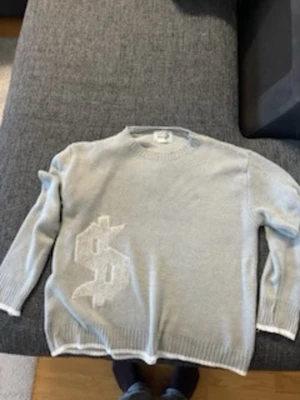 Ljusgrå stickad tröja buy Happiness - Ljusgrå stickad tröja från buy Happiness med ett stort vitt dollartecken på framsidan och texten 'my happiness' i vitt på ryggen. Tröjan har rund halsringning, långa ärmar och ribbade muddar. Perfekt för dig som gillar statement-plagg.