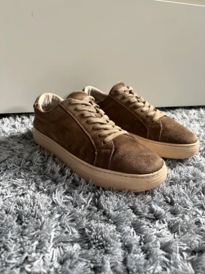 Bruna vagabond mocka - Snygga sneakers i brun mocka med beige, tjock sula och matchande bruna skosnören. Klassisk låg modell som passar till det mesta och ger en stilren look. Perfekta för dig som gillar en enkel men trendig stil. Ordinarie pris brukar ligga runt 1000kr så passa på nu
