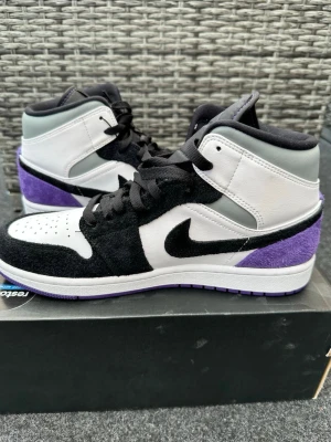 Air Jordan 1 Mid svart/vit/lila - Snygga Air Jordan 1 Mid sneakers i svart, vitt och lila. Helt oanvända. Kvitto finns via Mail. Köpta från restocks