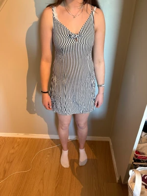 Randig kort sommarklänning - Randig klänning från H&M. Fin till sommaren. Det är väldigt lätt tyg så man blir inte jättevarm i den. Knyte vid bröstet