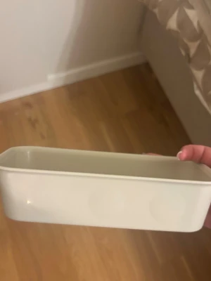 Vit rektangulär plastlåda - En enkel vit rektangulär låda i plast, perfekt för förvaring av småsaker, pennor eller andra prylar. Lådan har släta kanter och en minimalistisk design som passar in i de flesta rum.