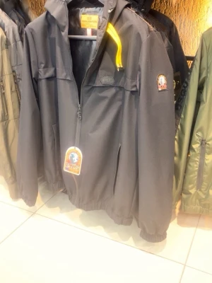 Svart vindjacka från Parajumpers finns alla storlekar - Snygg svart vindjacka från Parajumpers med gul detalj vid kragen och klassisk PJS-logga på ärmen. Jackan har dragkedja framtill, två sidofickor och elastiska muddar vid ärmslut och nederkant. Tillverkad i ett lätt och slitstarkt material som står emot vind kan inte mindre än 899