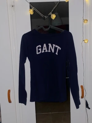 Mörkblå långärmad topp från GANT - Snygg mörkblå långärmad topp från GANT med vit logga tryckt över bröstet. Im princip helt oanvänd. 