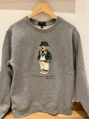  Polo Bear sweatshirt från Ralph Lauren storlek S - Väldigt fint skick, knappt använd – inga fläckar eller slitningar. Klassisk grå färg med ikoniska Polo Bear-trycket. Passar perfekt till en clean outfit eller vardaglig streetwear. Nypris ca 2000–2500 kr Mitt pris: 899 kr. Hör av er!