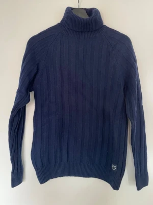 GANT stickad polotröja marinblå - premium knit - storlek M - Stilren och lyxig stickad polotröja från GANT i klassisk marinblå färg. Ribbad struktur och hög krage som ger en riktigt snygg och tidlös look - perfekt för både vardag och mer uppklädda outfits.  ✔ Väldigt fint skick ✔ Mjuk och skön kvalitet ✔ Premiumkänsla i både material och passform ✔ Lätt att matcha till jeans, chinos eller lager-på-lager  Material: 80% bomull / 20% polyamid – slitstark och behåller formen bra.  Storlek M  Kan skicka mått vid intresse  🧼 Tvättad innan försäljning 📦 Snabb fr