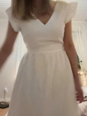 Vit omlottklänning med volangärm - Söt vit klänning med omlott-v-ringning och volangärmar. Kjolen är lätt utställd och klänningen har en markerad midja. Perfekt för sommarens alla tillfällen. Materialet ser ut att vara bomull eller en bomullsblandning. Köpte den till studenten från Sellpy, men den är från shein. Den är jättefin och sitter fint men valde en annan så nu säljer jag den vidare.