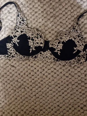 Intimissimi bh 75b - Snygg mörkblå bh från intimissimi med vit spetsbrodyr och bygel. Perfekt för dig som gillar en elegant och feminin stil. Justerbara axelband för bästa passform. OBS: Bh:n ser svart ut på bilden men är marinblå 💘