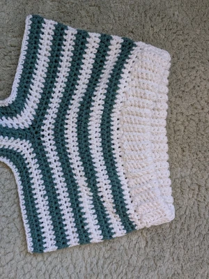 Randiga virkade shorts i grönt och vitt - Unika virkade shorts med bred resår i midjan. De har gröna och vita ränder och är virkade i bommullsgarn. Lowwaist och ganska kort innerbenslängd. Perfekta för sommarens alla äventyr och riktigt snygga till en enkel topp. Storlek XS, passar även S då de är stretchiga. Aldrig använda. Handgjorda, därav priset.