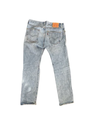 Levi's ljusblå raka jeans 32/32 - Klassiska ljusblå jeans från Levi's med rak passform och knappgylf. Jeansen har fem fickor och den ikoniska läderlappen bak i midjan. Tillverkade i slitstark denim, perfekta för en avslappnad och trendig look.