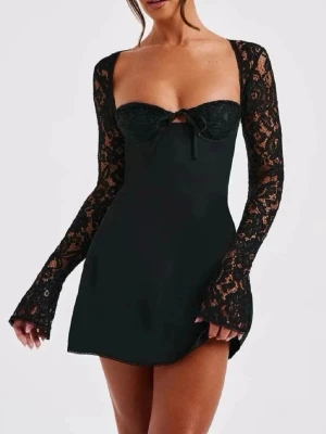 Svart spetsklänning med snörning - Kort svart klänning med långa spetsärmar och öppen rygg. Klänningen har snörning i ryggen och en liten rosett framtill. Materialet är en mix av spets och polyester, vilket ger en elegant och trendig look. Har aldrig använts