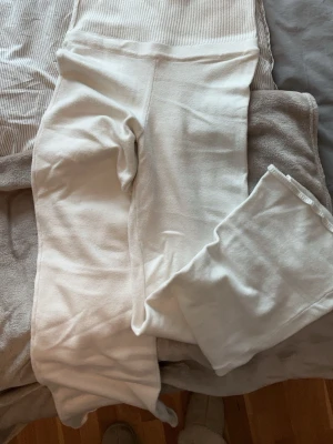 Vita stickade byxor med ribbad midja - Stickade mjukisbyxor med ribbad midja som man viker ner. Använda ett flertal gånger men har inga defekter. 