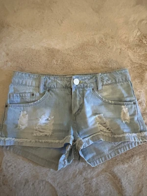 Ljusblå lågmidjade jeansshorts - Ett par lågmidjade jeansshorts i strl XS. Dragkedjan är trasig och därav priset sänk. 