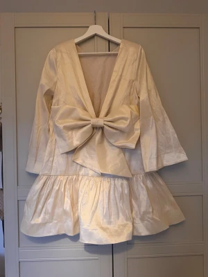 klänning med rosett S student  - Storlek s från bubbleroom, använd vid ett tillfälle. Perfekt till student eller sommarens festligheter.  Ljus champagnefärgad 