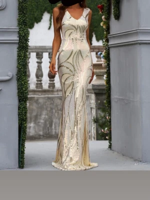 Lång glittrig klänning i champagne - Elegant långklänning i champagnefärg med glittriga paljettdetaljer och v-ringad hals. Klänningen har ärmlös design och figurnära passform som framhäver siluetten. Perfekt för speciella tillfällen där du vill sticka ut.