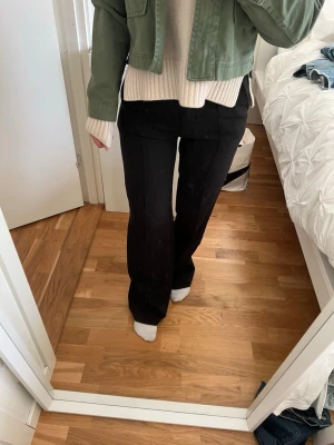 Svarta kostymbyxor med pressveck - Säljer ett par svarta kostymbyxor med raka ben och pressveck. Byxorna har hög midja och klassisk passform som ger en clean och stilren look. Perfekta att matcha med både stickad tröja och kavaj. Materialet känns mjukt och följsamt.