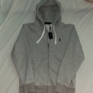 Helt ny hoodie från PRL - Helt ny grå zip hoodie från polo ralph lauren som är super grisch. Säljer pga att den inte passar. Den lutar lite mer åt M hållet i storlek.