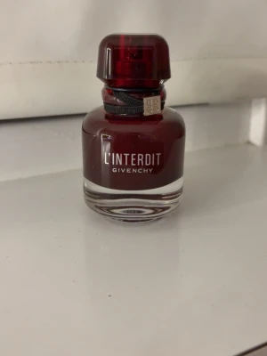 Givenchy L’Interdit Rouge parfym  - Givenchy L’Interdit Rouge Eau de Parfum i en elegant, mörkröd glasflaska. Doften är blommig med träiga och kryddiga toner, perfekt för dig som gillar romantiska och unika parfymer. Passar för dig som vill sticka ut lite extra! En väldigt god och  komplimang givande parfym men tyvärr kommer den aldrig till användning (endast använd 1-3 gånger) 