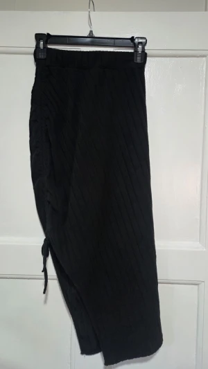 Svart ribbad långkjol med snörning - Aldrig kommit till användning, men den är super fin. Säljer en svart långkjol med ribbad struktur och snörning i sidan. Kjolen har en avslappnad passform och resår i midjan för extra komfort. Perfekt för dig som gillar en enkel men ändå snygg stil.